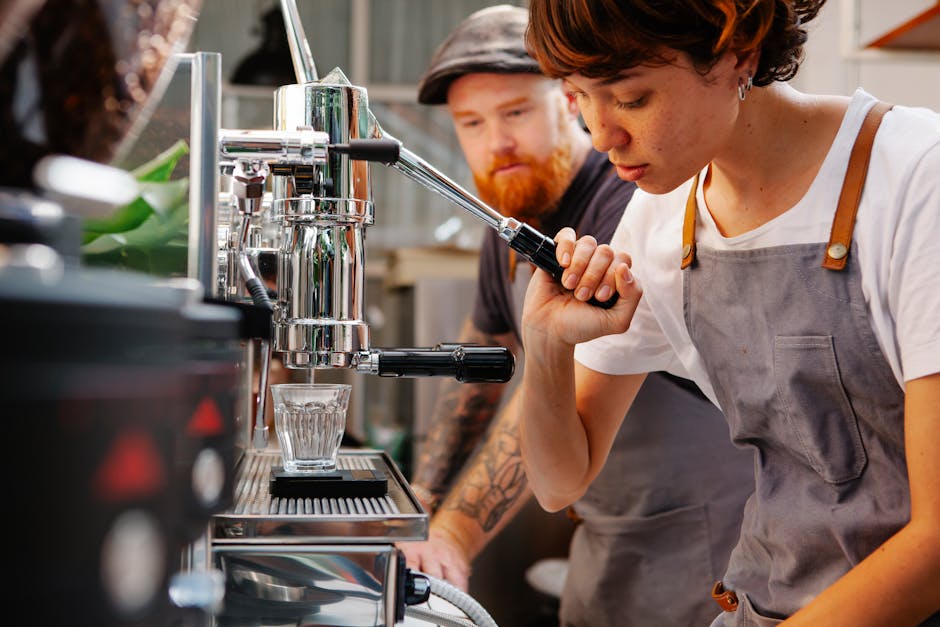 Crop female employee touching lever of professional coffee maker pouring water into glass against bearded partner in cafeteria